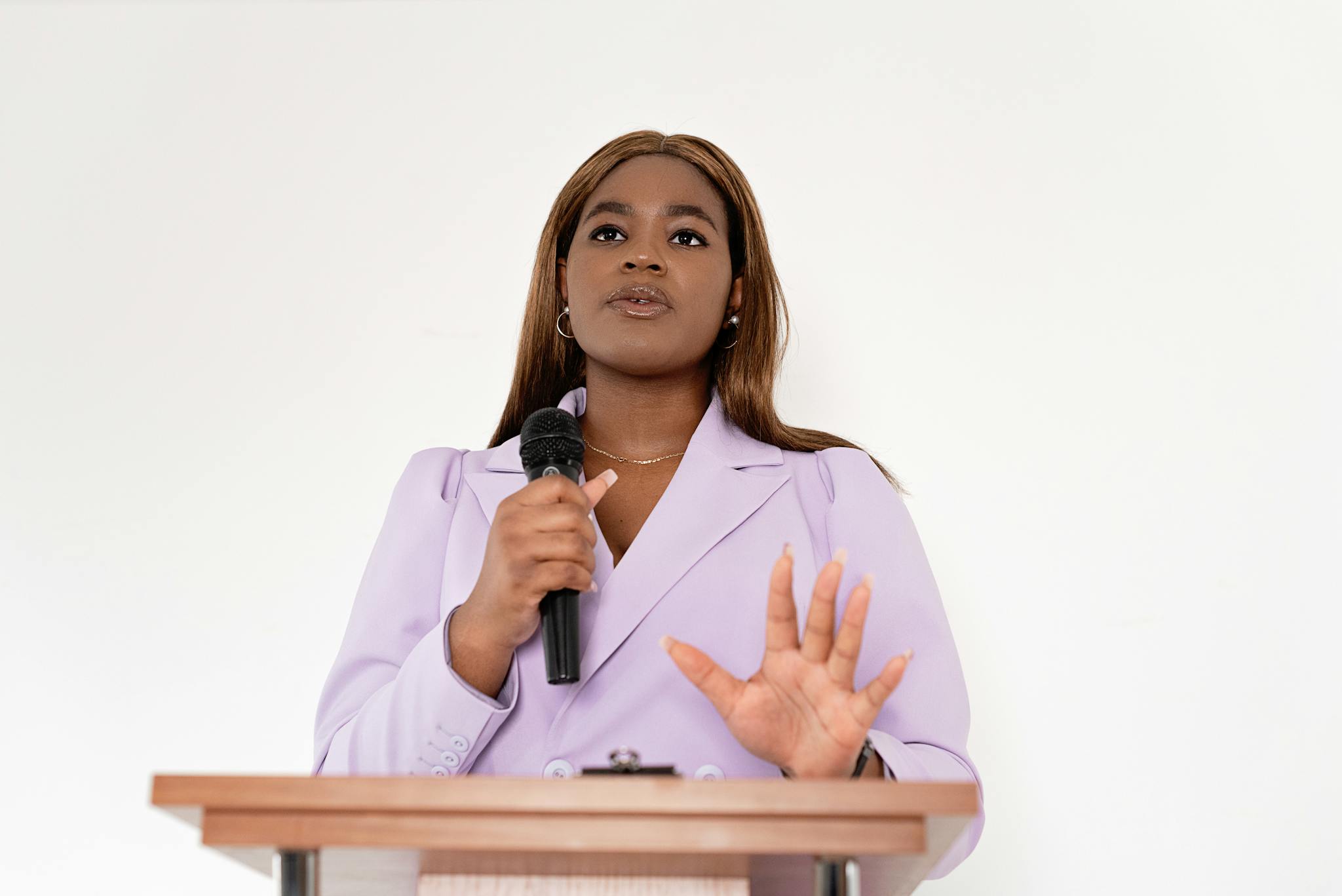 Confident black woman speaking at a podium with a microphone, showcasing leadership and professionalism.